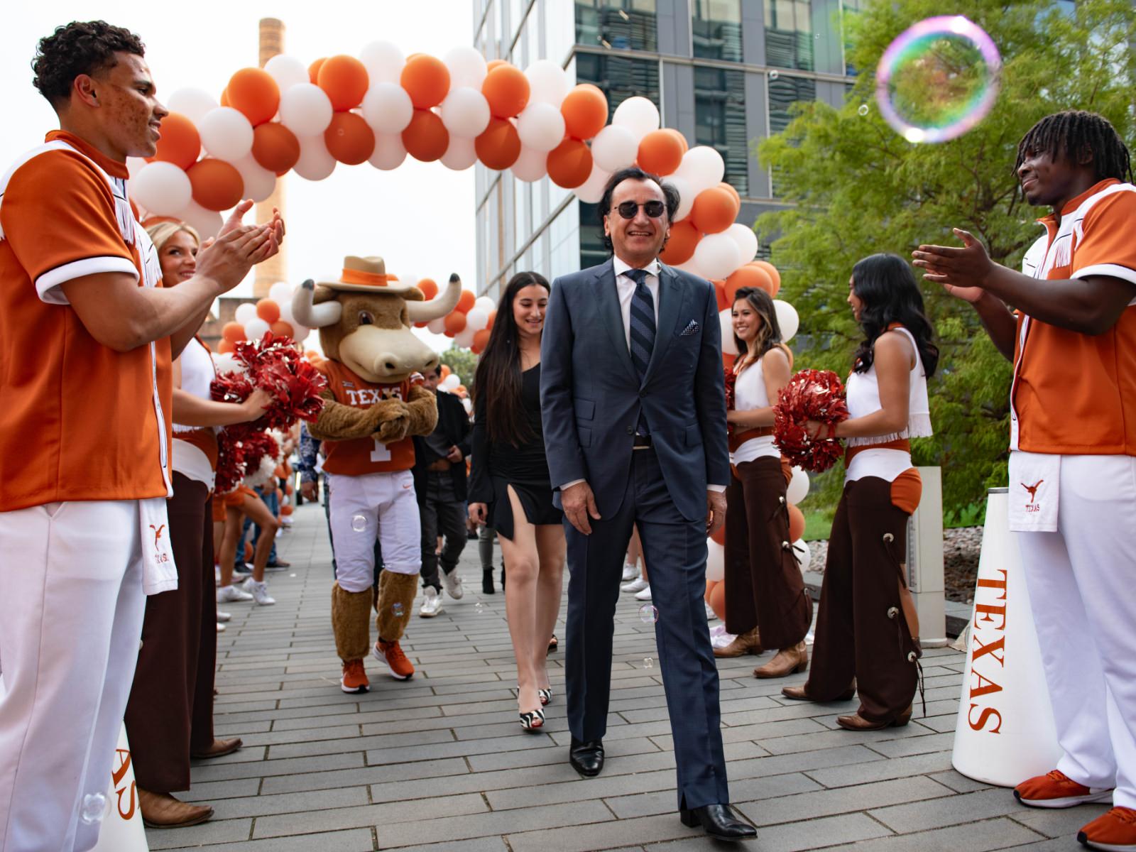 Fariborz Maseeh walking under balloon arch with cheering Texas engineering students