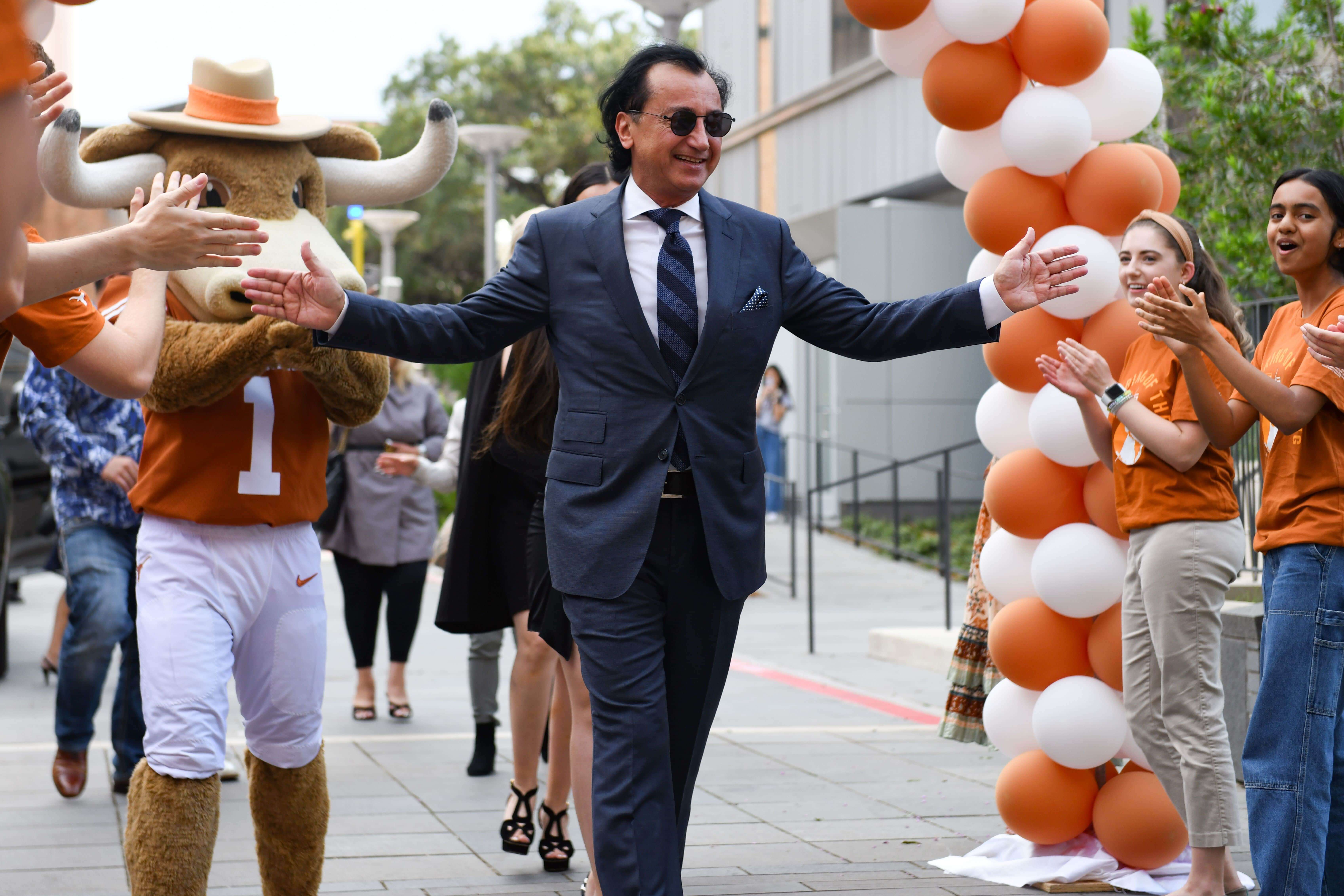 Fariborz Maseeh walking under ballon arch with UT Austin mascot, Bevo