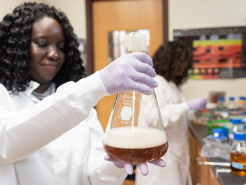 Engineering student in biotechnology lab holding beaker