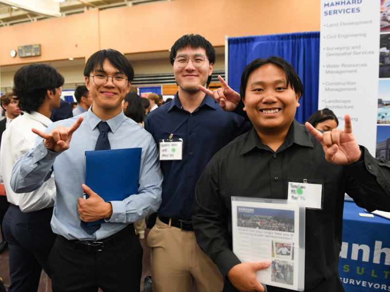 Texas Engineering students smiling and doing hook 'em horns near recruiter booths