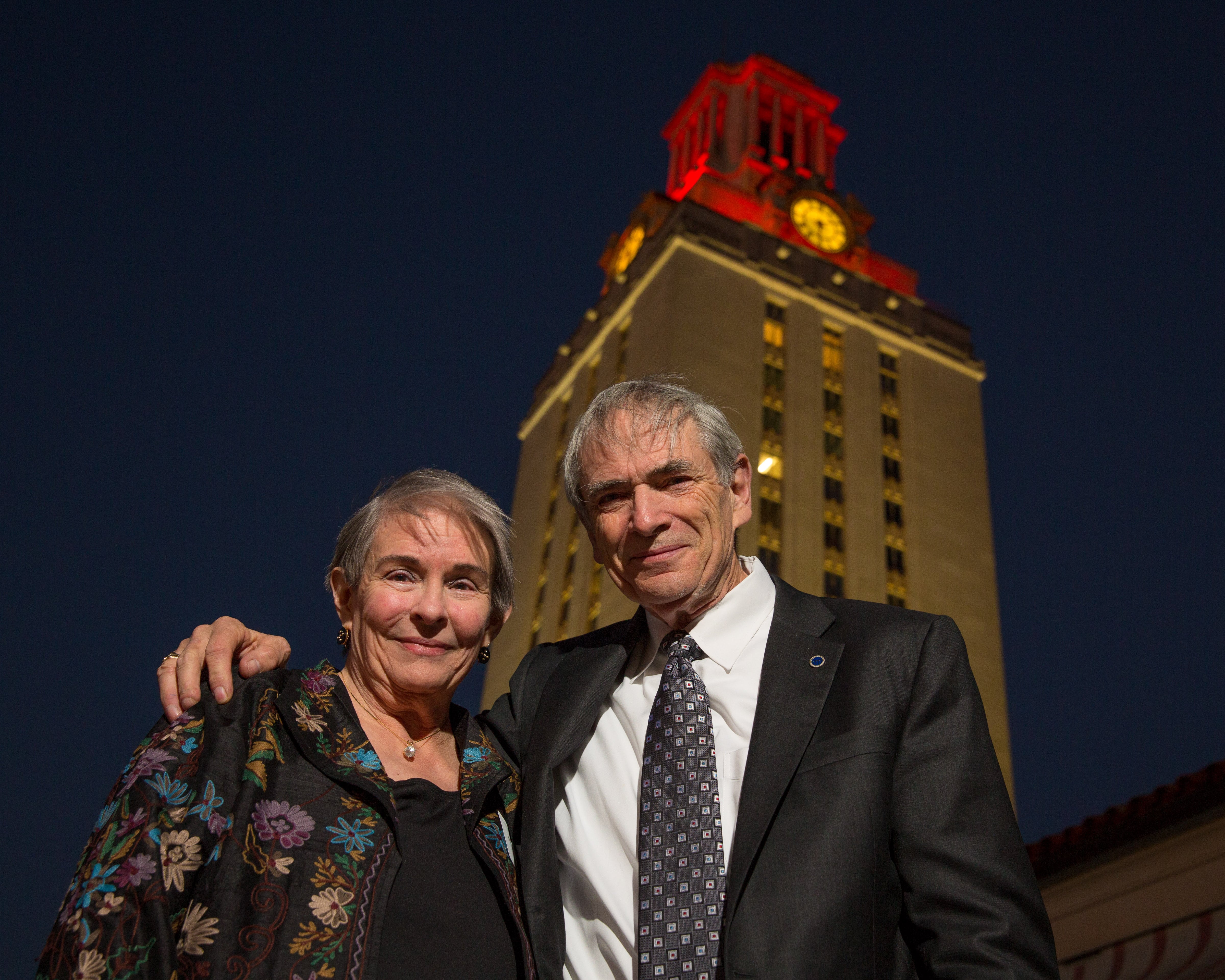 J. Tinsley Oden and his wife Barbara smiling in front of UT Tower lit up at night