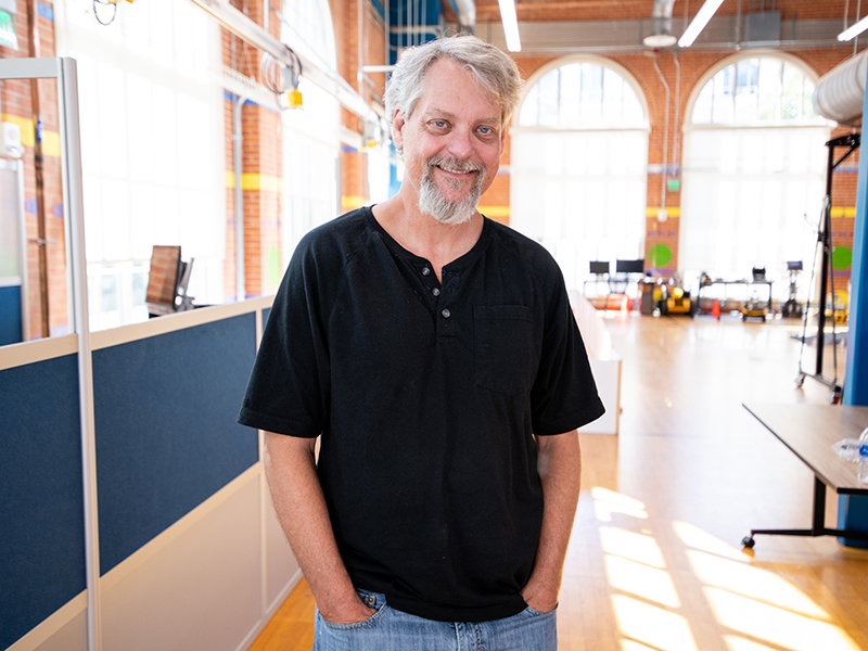 Mitch Pryor Mitch smiling in front of large widows at Robotics lab