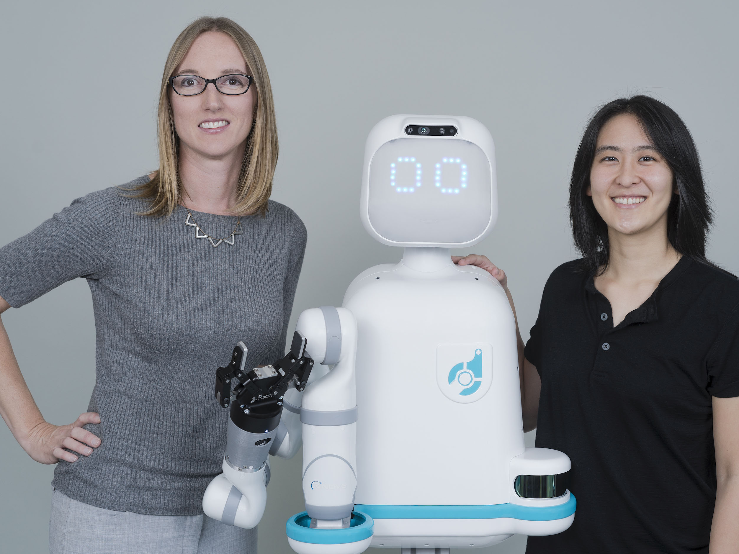 Photo of Andrea Thomas and another researcher with their robot Moxi.