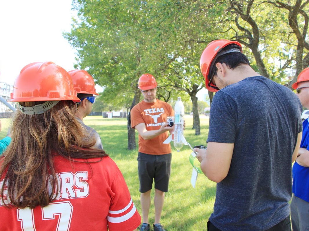 Texas engineering students wearing hard hats writing notes