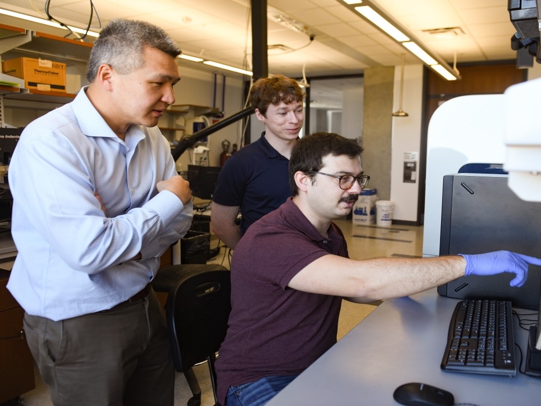 Texas Engineers huddled around a computer in a lab.