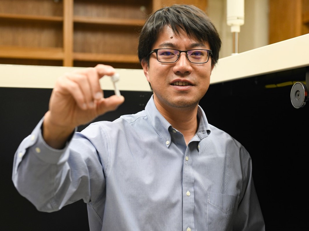 Texas Engineer Yijin Liu holds up a wireless headphone in a lab.