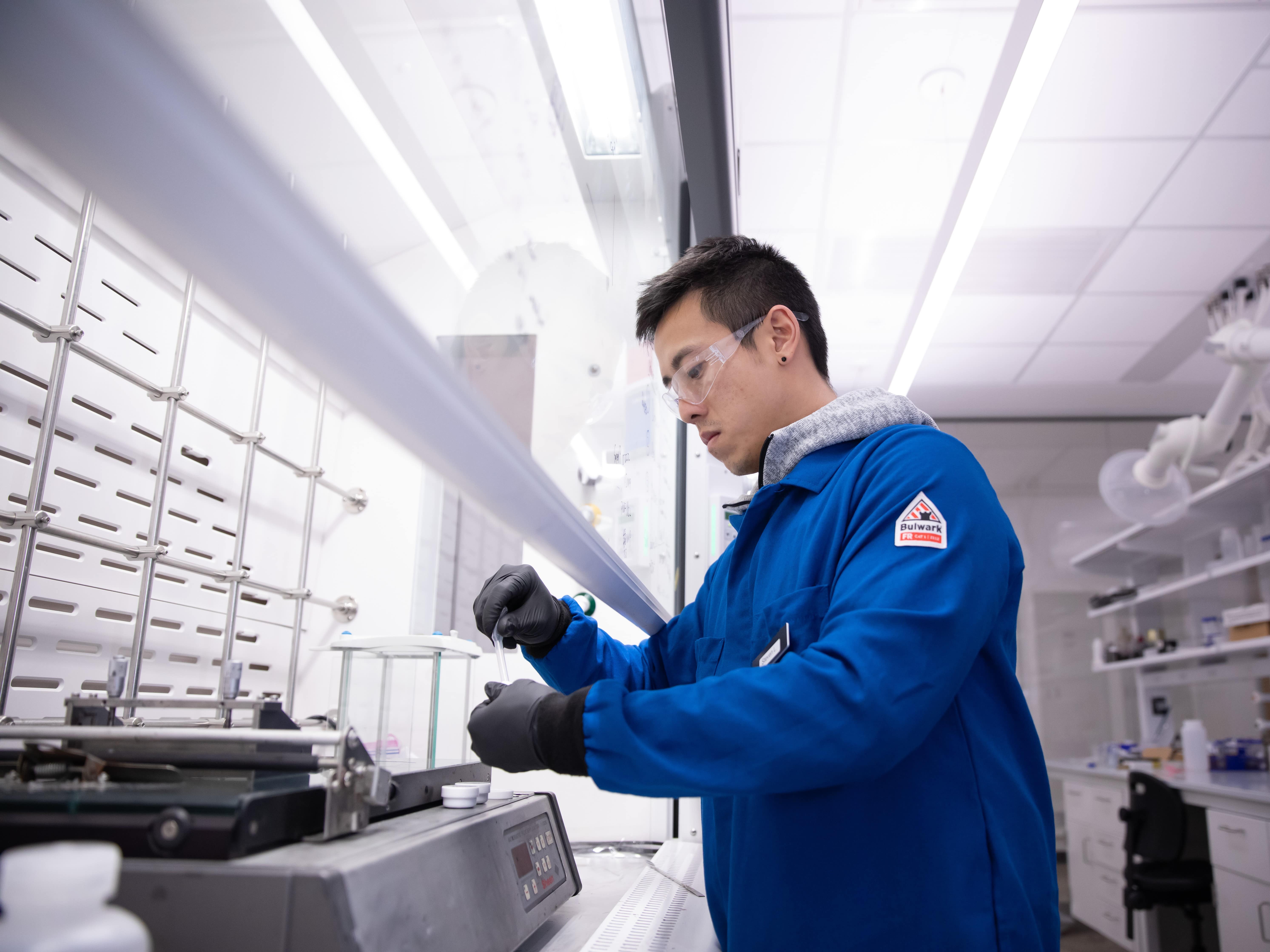 Steven Lee, a Texas engineering graduate student, holding small equipment in Arumugam Manthiram's lab