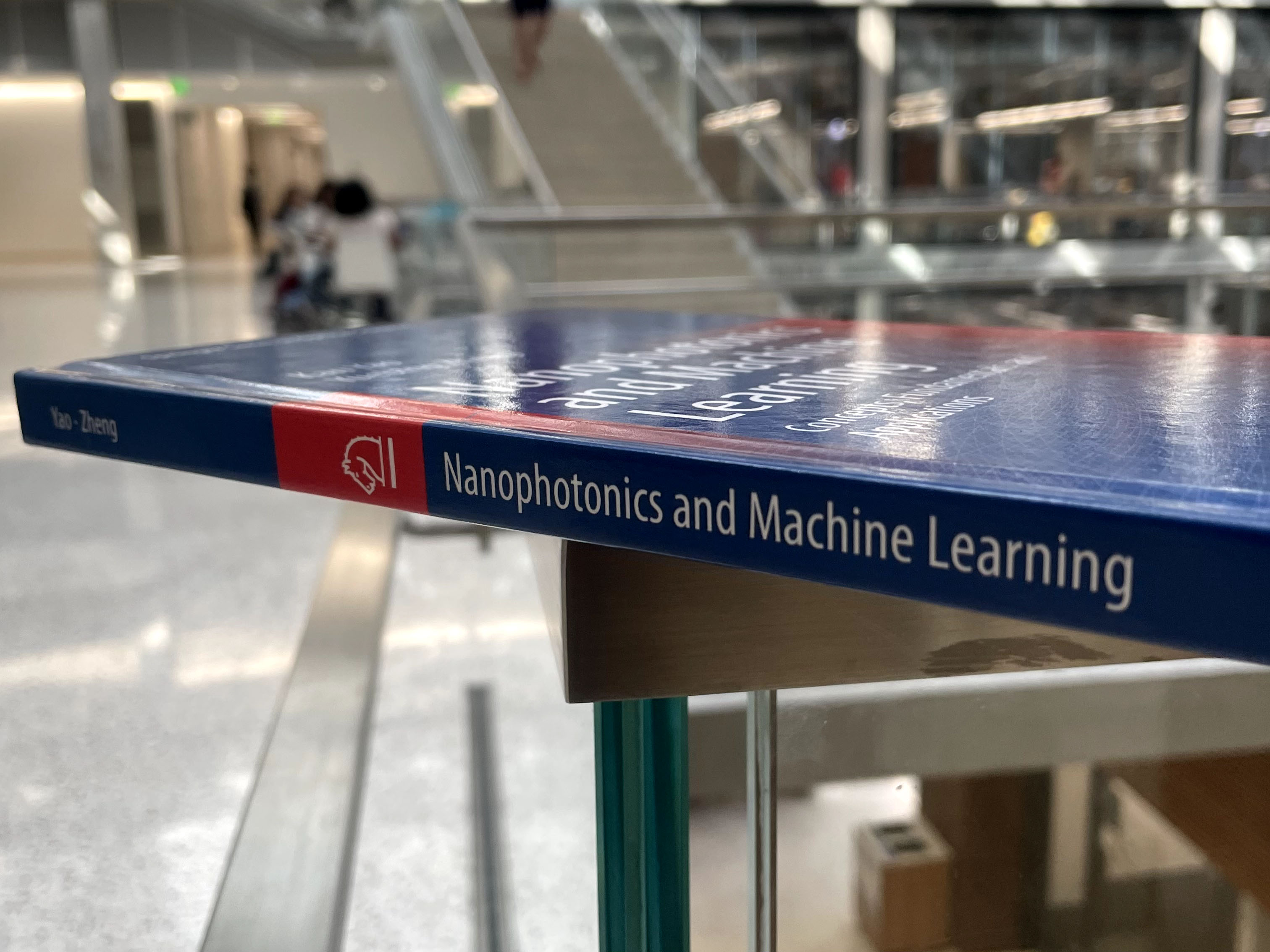 Nanophotonics and Machine Learning book balanced on a guardrail