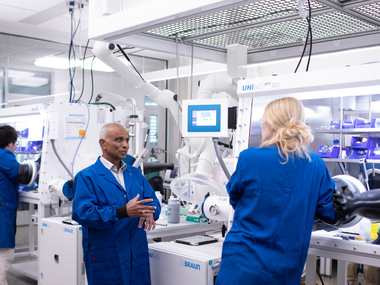 Texas engineering faculty talking in a research lab next to large equipment