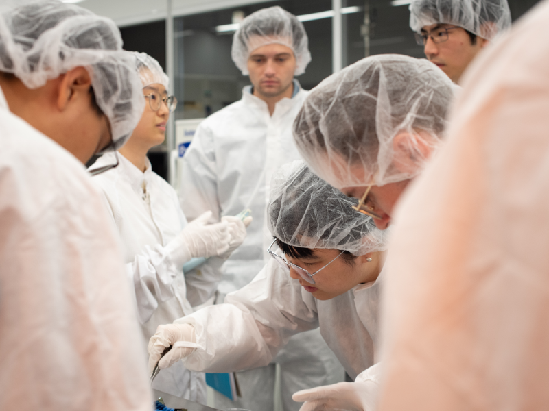 Texas Engineering students in lab gear gathered in semiconductor lab