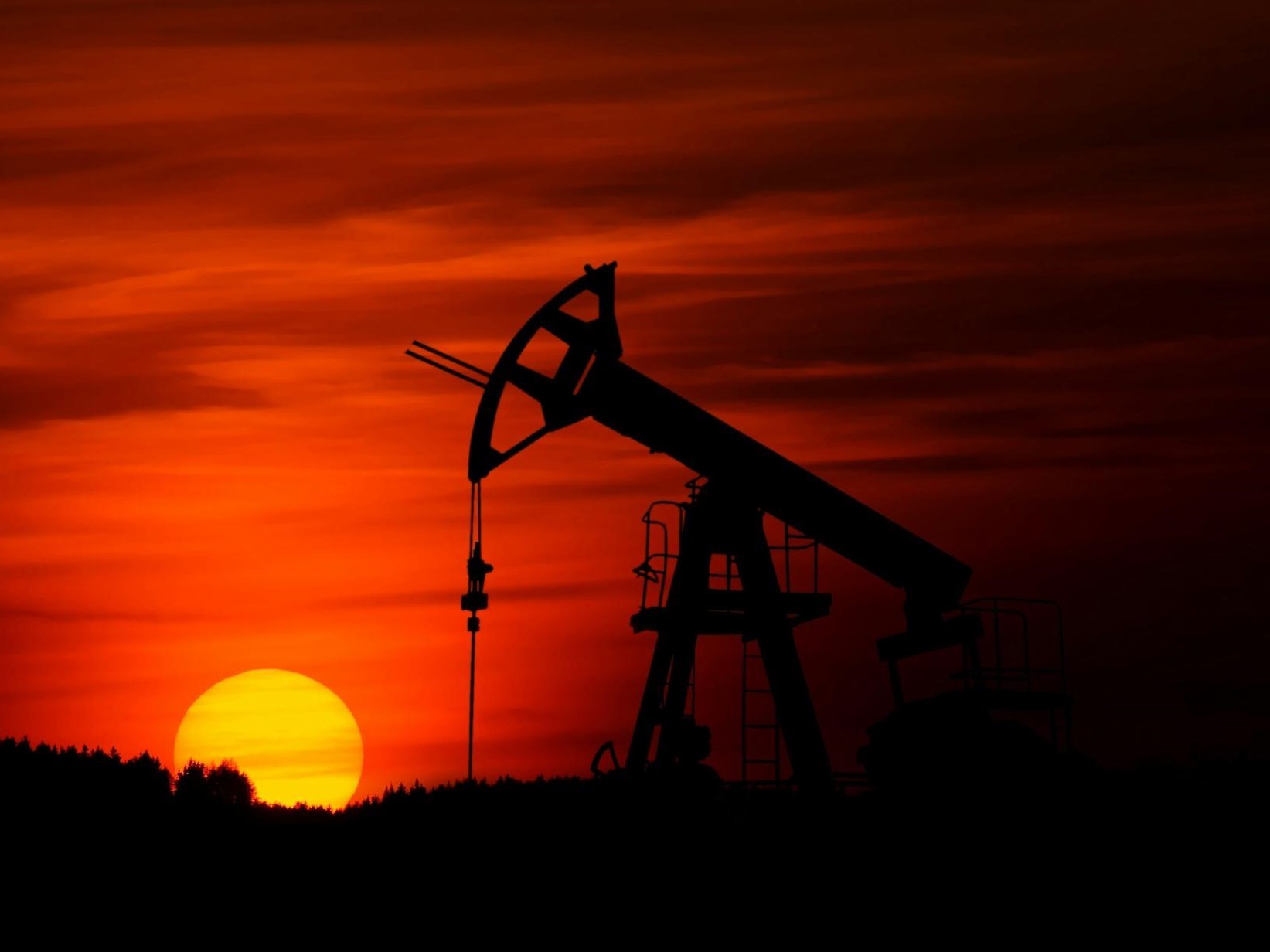 An oil rig backlit by the sunset