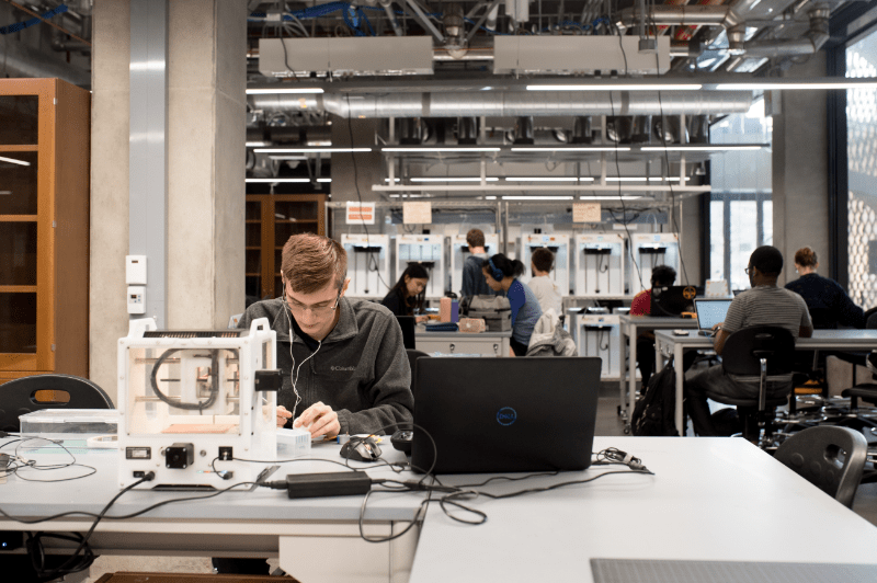 Texas engineering student at worktable with headphones in at Texas Inventionworks