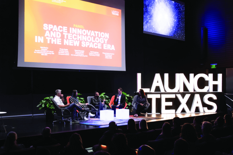 Stage of panelists at Launch Texas event with screen behind them