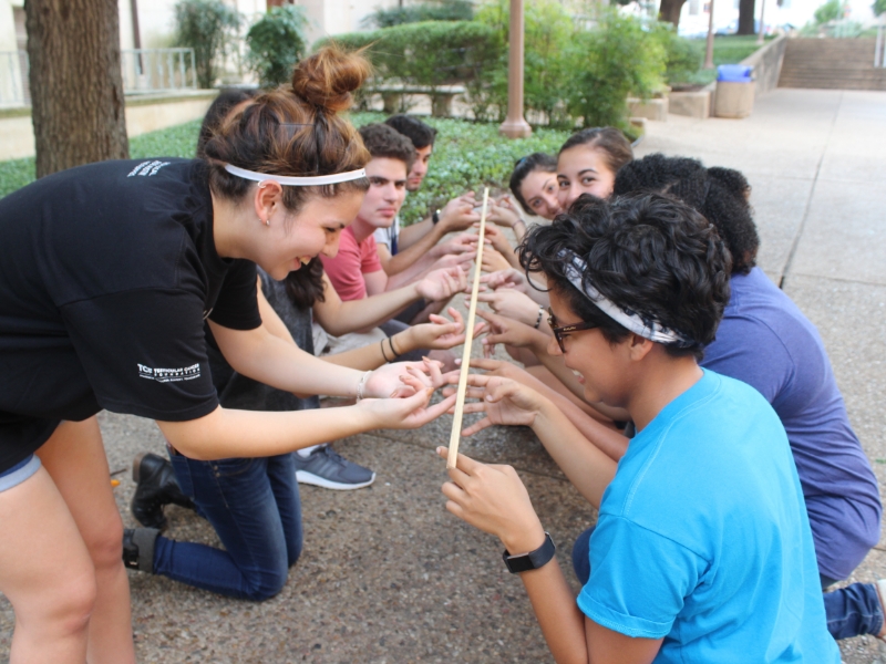 Texas engineering students holding a long piece of wood together