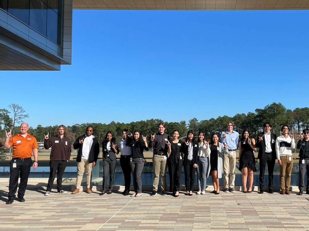 Group of students with Exxon representative doing hook 'em horns