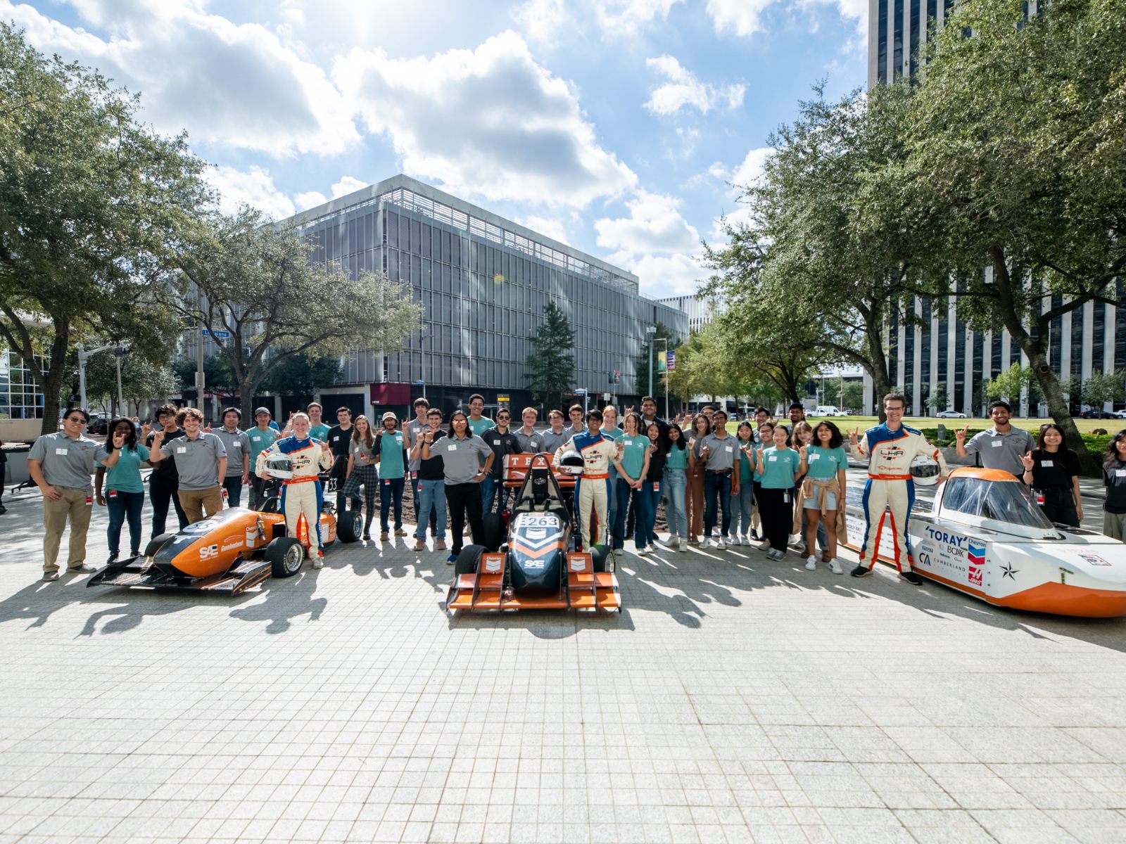 large group of Texas engineering standing next to racing vehicles