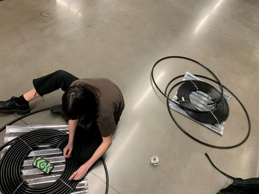 Cockrell student sitting on tile floor with biodigester parts