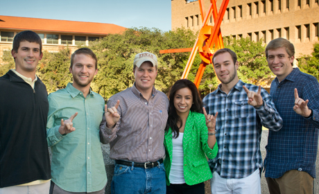 Texas Engineering students from the chemical engineering department smiling and doing hook 'em horns hand signs