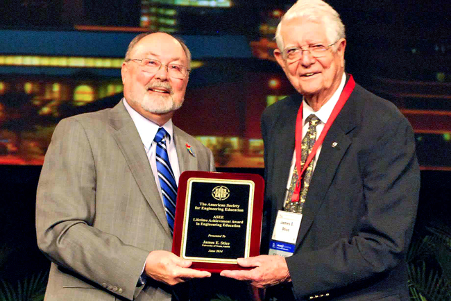 Professor emeritus James Stice holding Lifetime Achievement Award plaque at ceremony