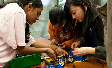 Three Texas engineering students working on a robotic car in WEP