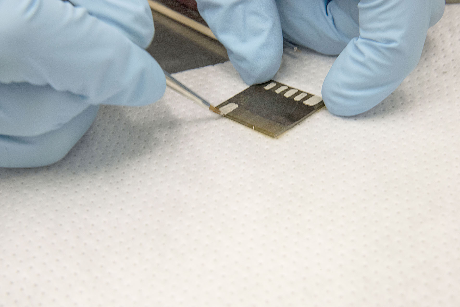 Gloved hands working on cellulose solar leaf prototype