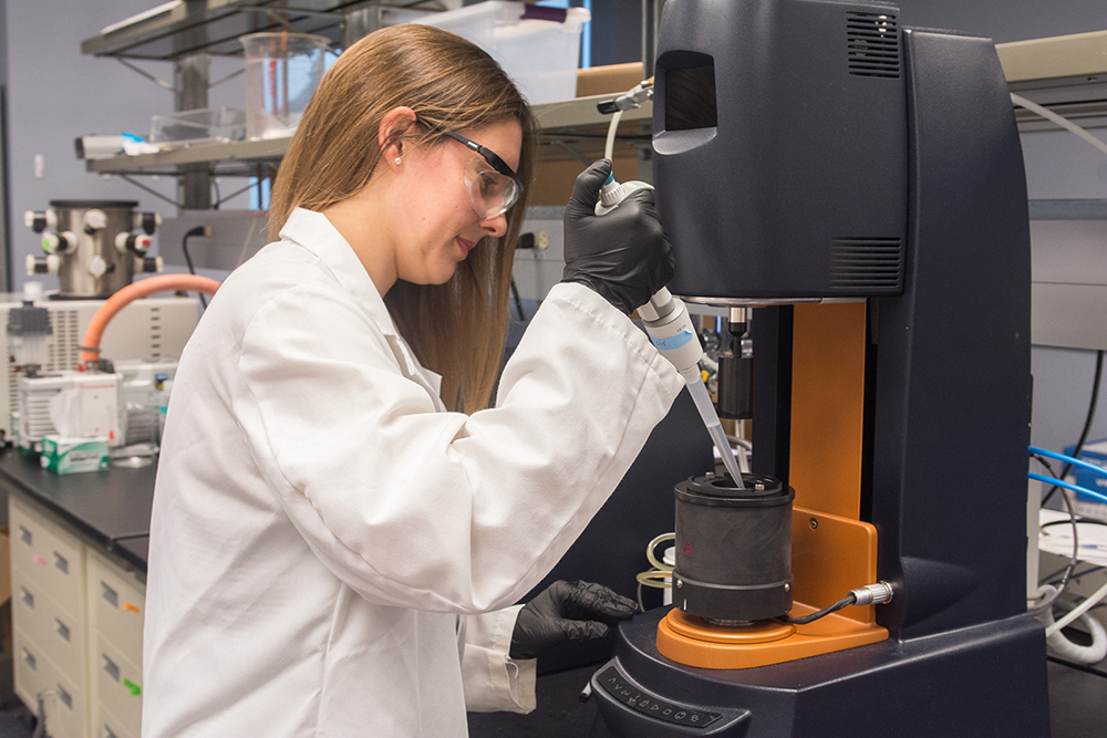Texas Engineering biomedical engineering student in lab coat working with lab equipment