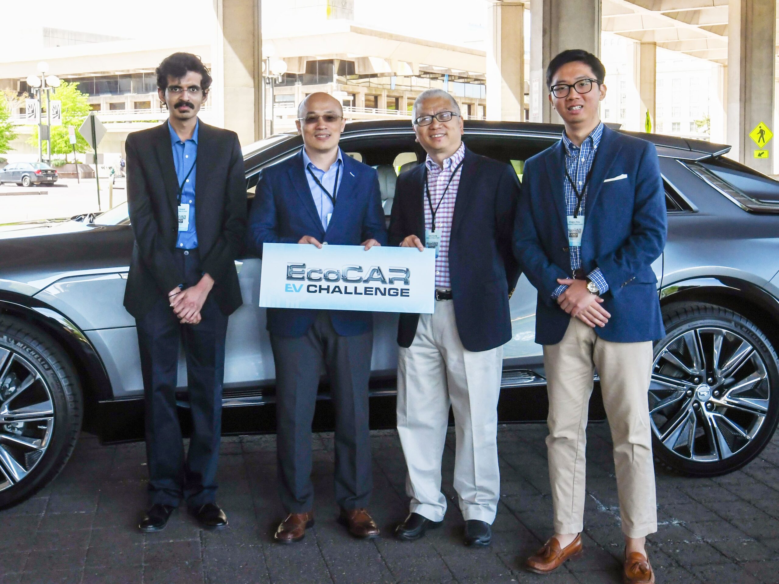 students and faculty in front of car