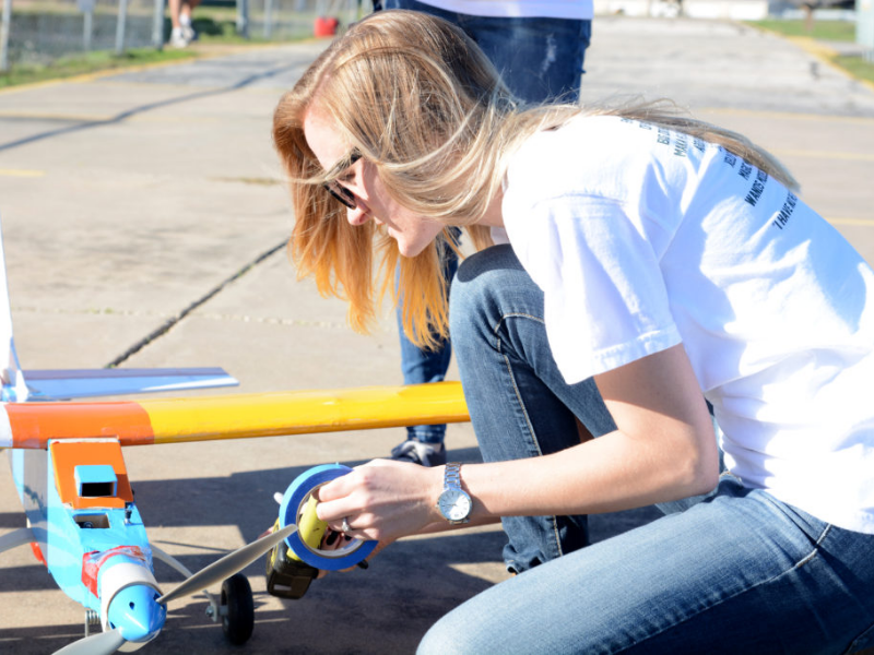 Texas Engineering student bent over a model plane