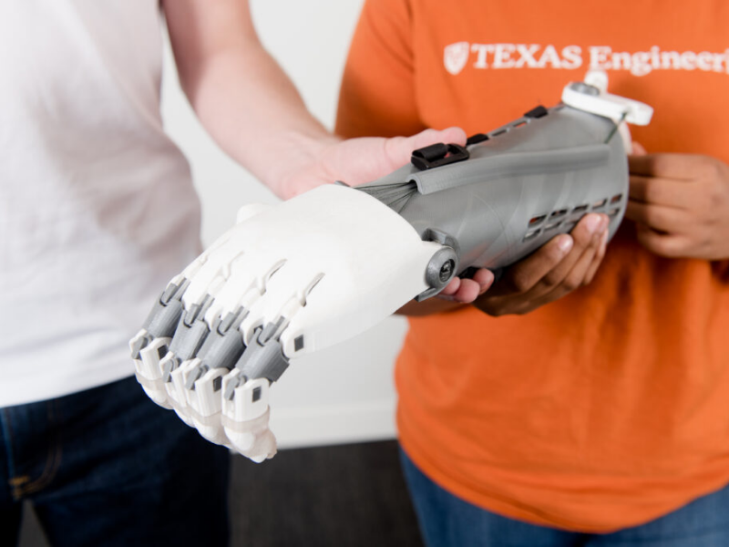 Texas Engineering students holding robotic arm