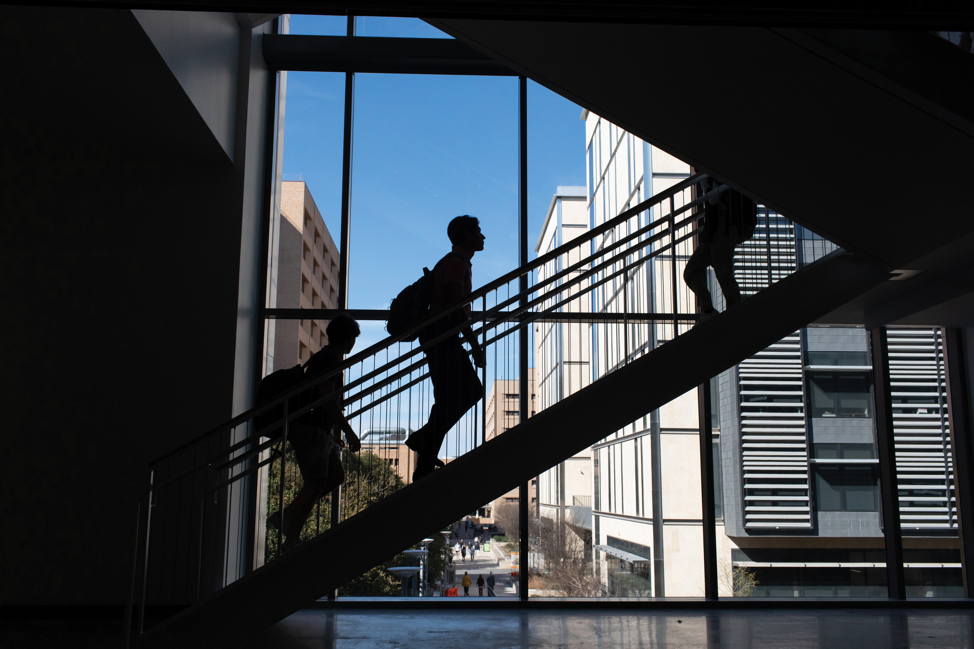 Silhouette of student walking up staircase within GLT building.