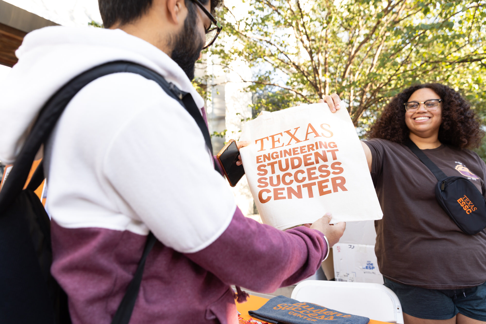 Staff hands student bag of materials to help start semester from Engineering Student Success Center.
