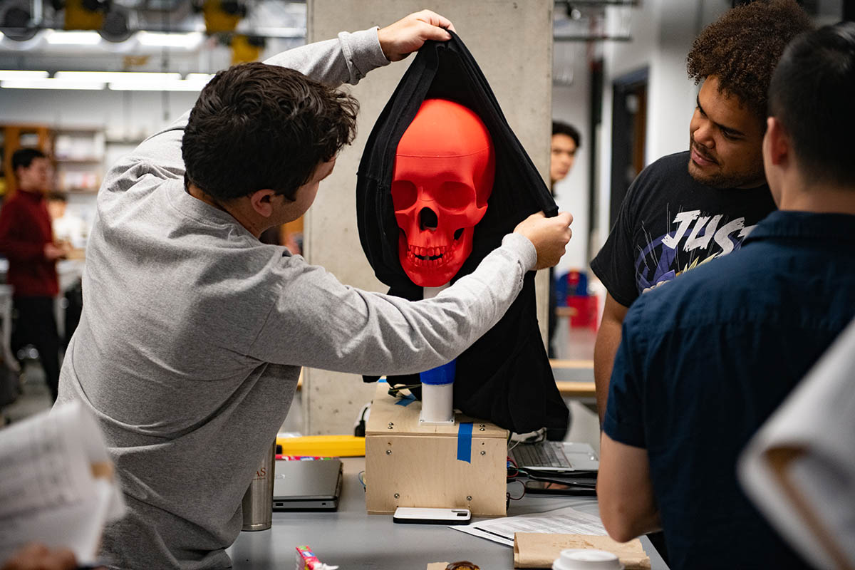 Students uncovering a red robot skull at UT Austin Inventionworks