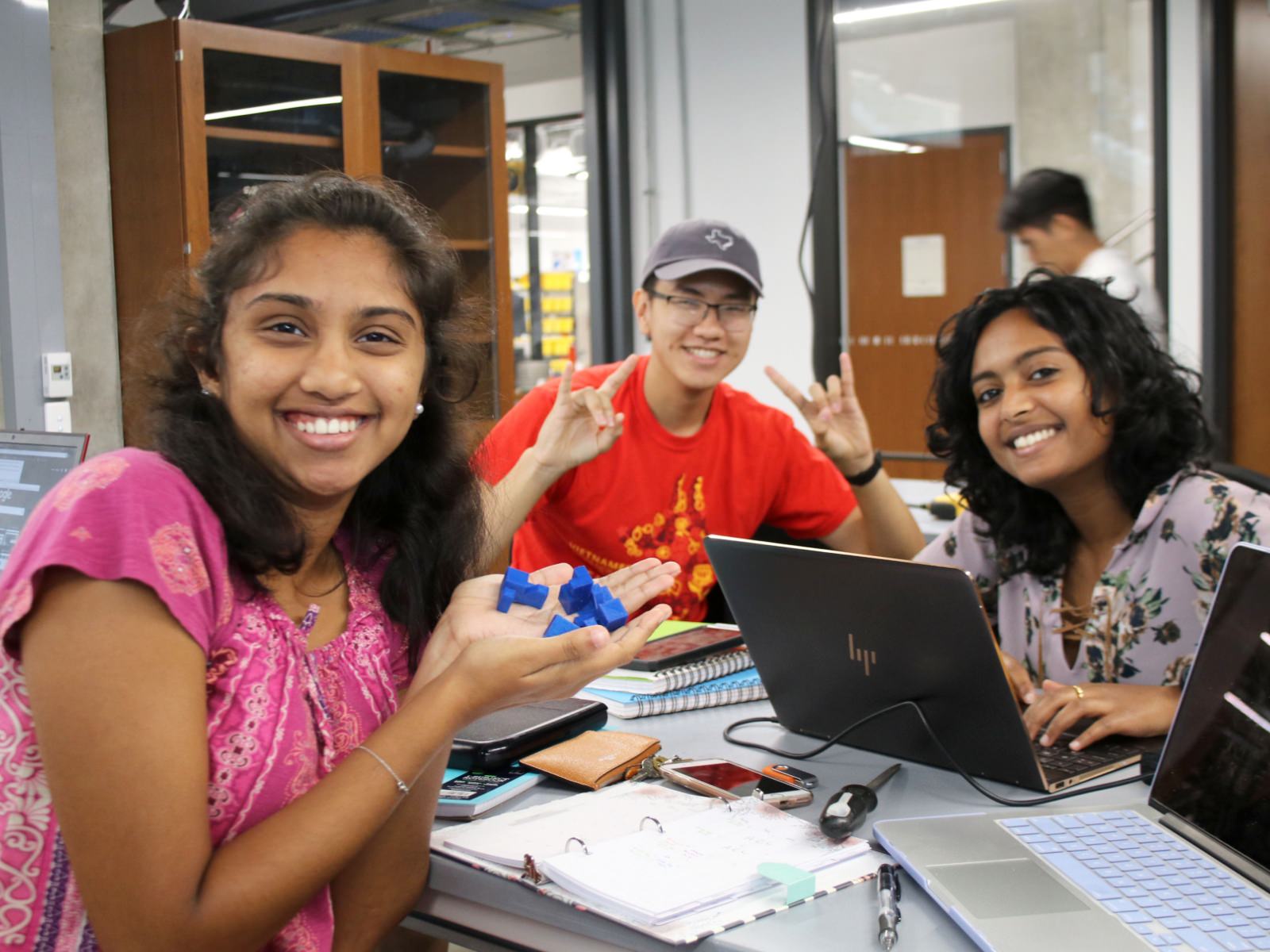 Texas Engineering students smiling in Texas Inventionworks while collaborating at table
