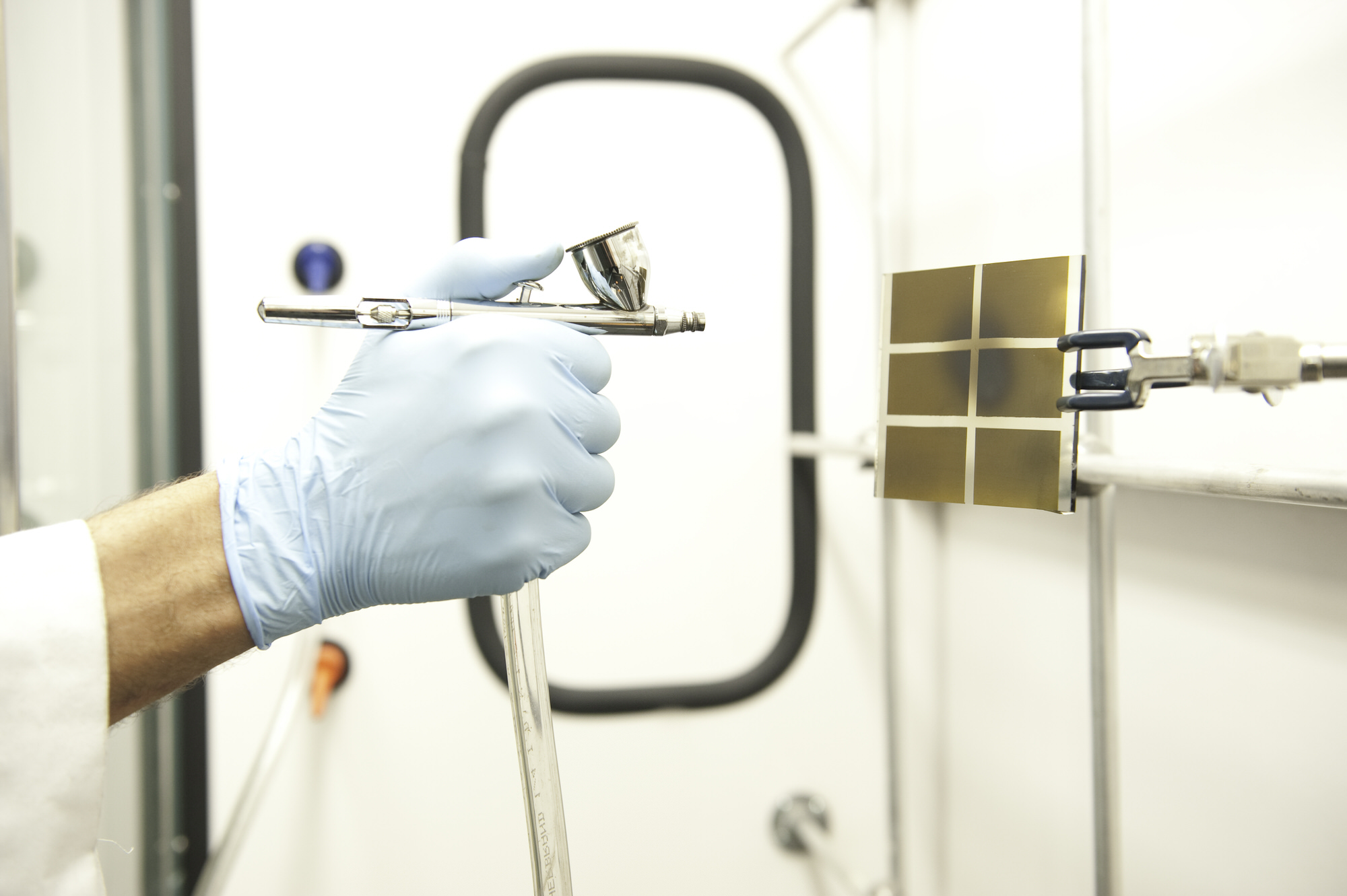 gloved hand operating precision research tools on solar panel prototype