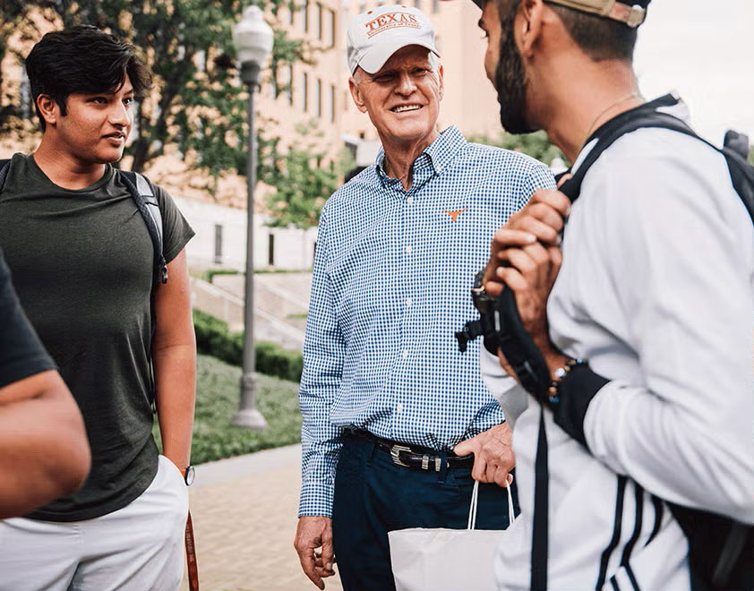 Gary thomas stands with students in front of a building.