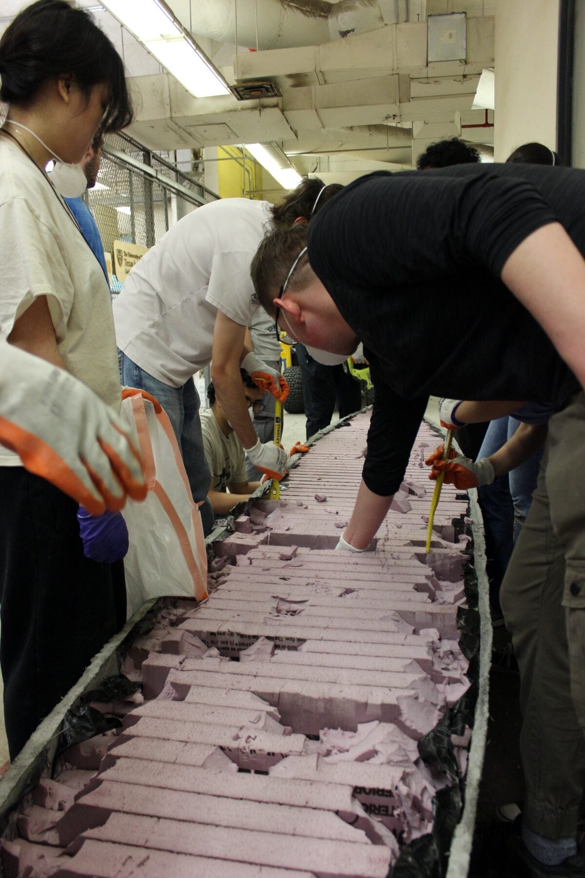 A large group of Concrete Canoe teammates work on their boat.