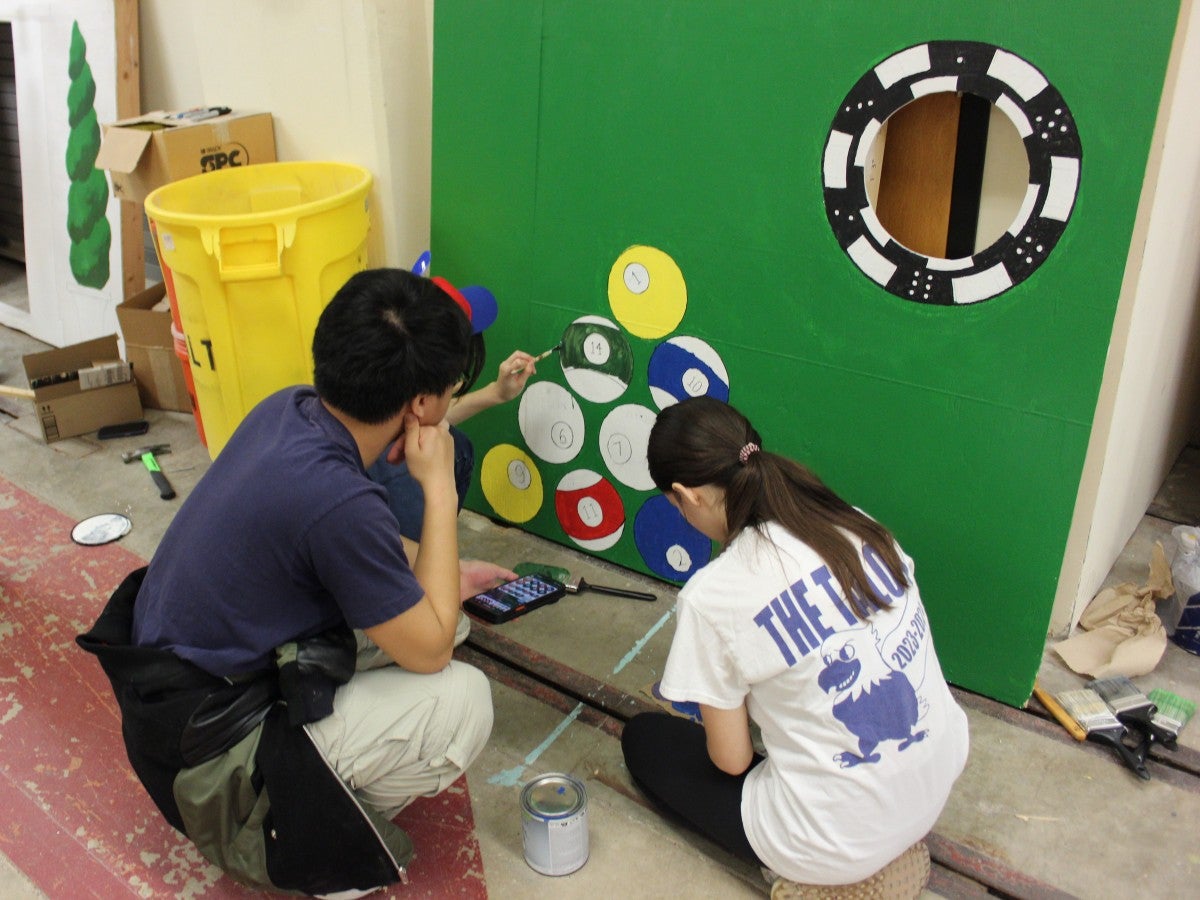 Concrete Canoe teammates painting a portion of their boat.