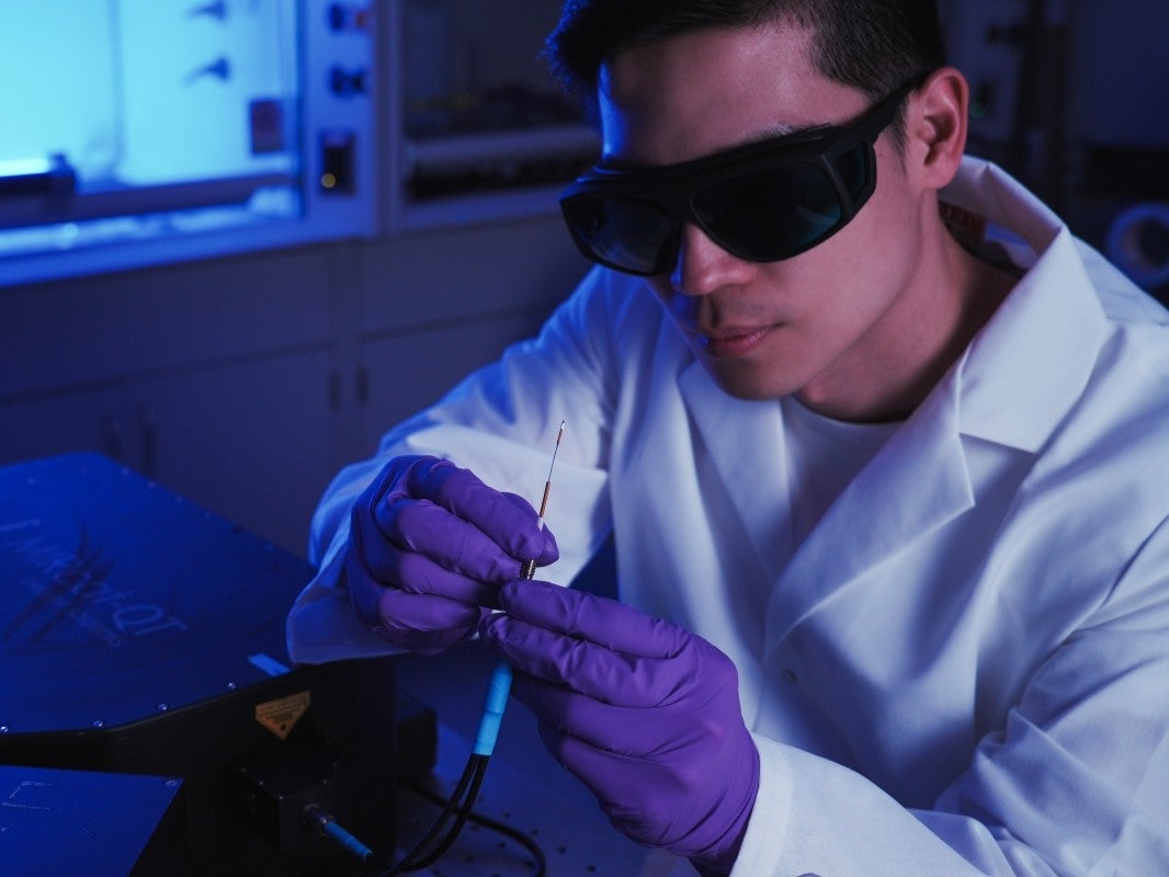 Texas Engineer Tse-Ang Lee holds a small biomarker probe in a lab.