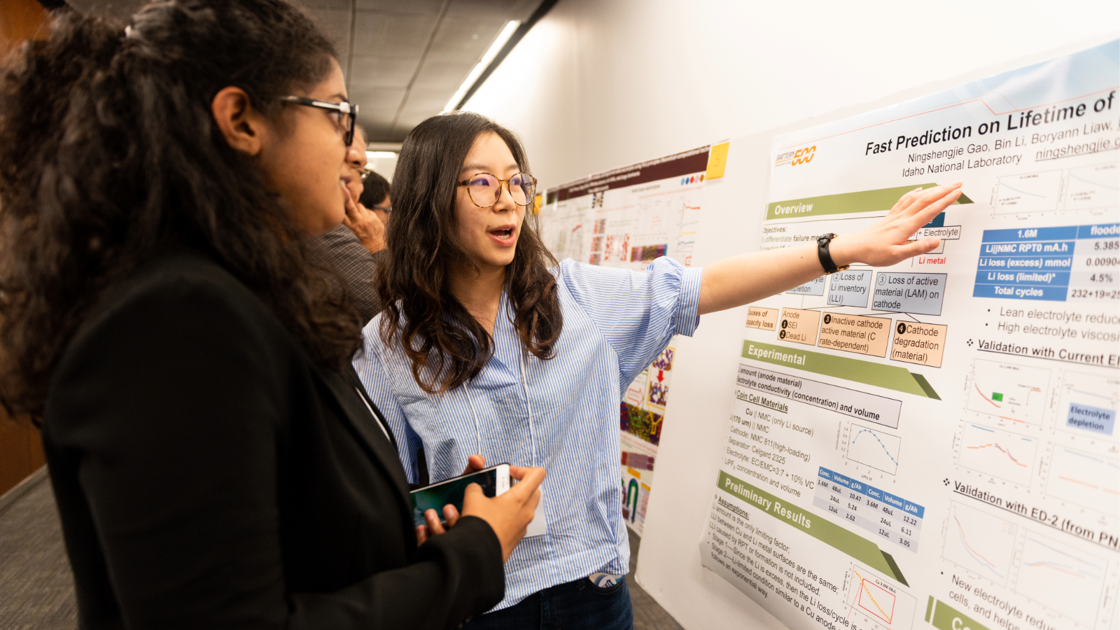 Texas Engineerins student pointing at research poster and explaining research to onlooker