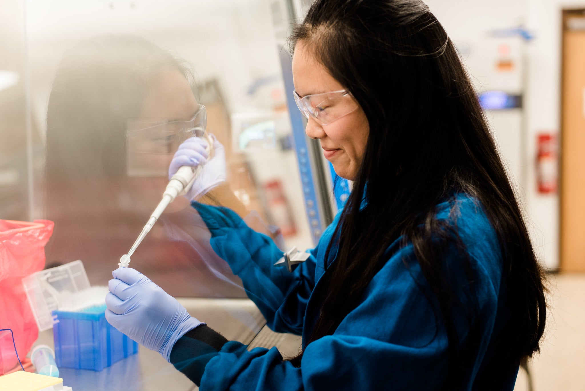 Texas Engineering researcher in lab safety gear using a dropper to transfer a substance into pteri dish