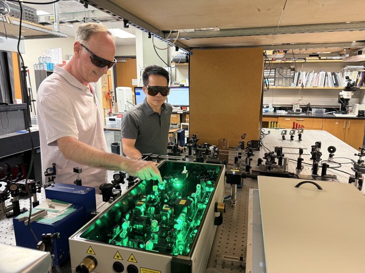Texas Engineers Andy Dunn and Hengfa Lu using a laser machine in the lab.