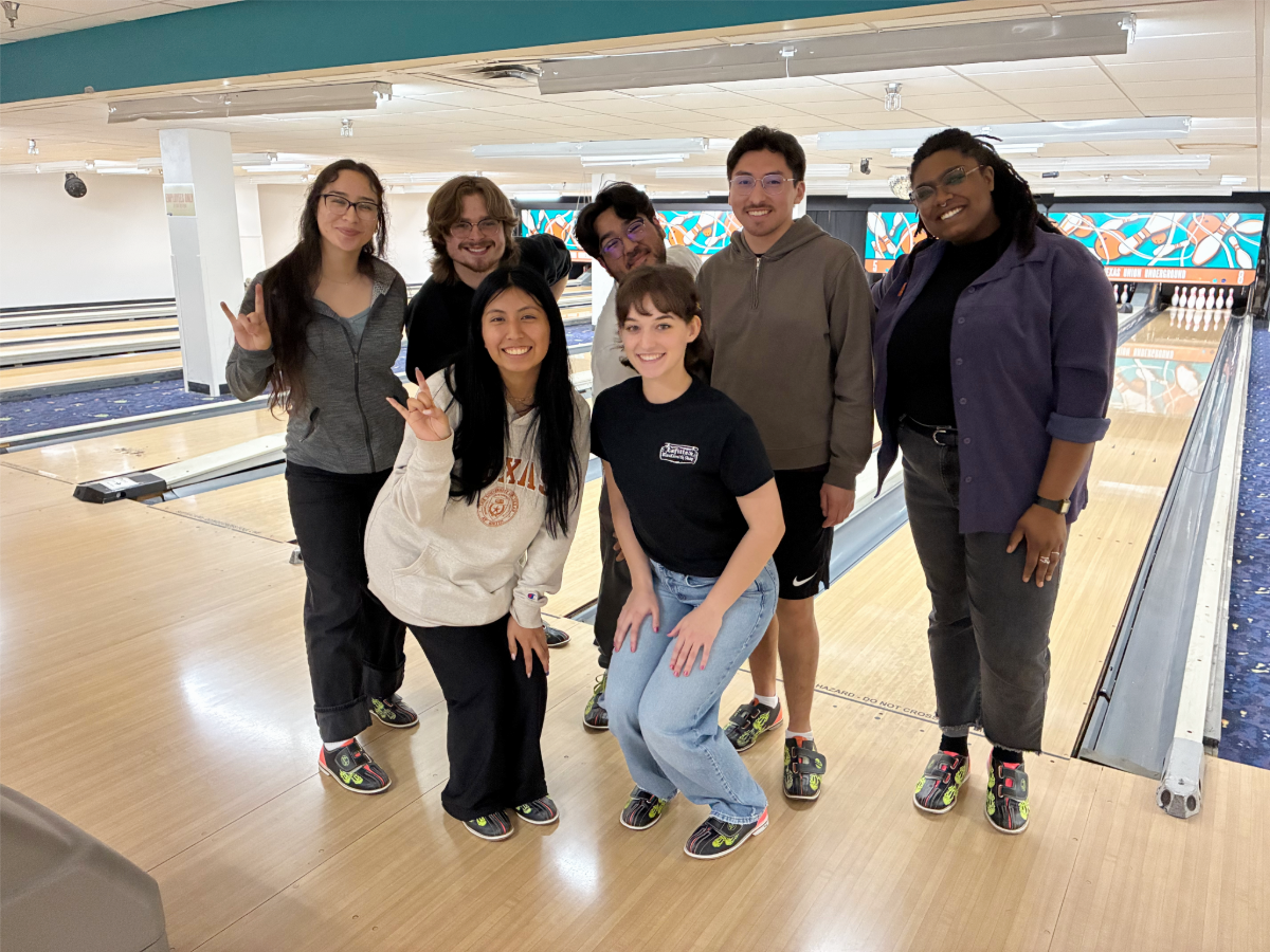TAAP students and program coordinator Darienne Coffee smiling together in front of bowling lanes.