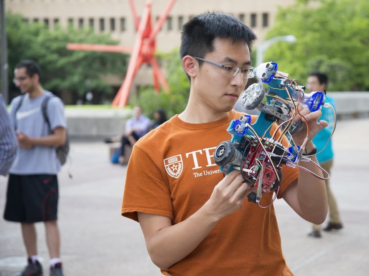 A Texas Engineering student holds a robotic car he developed.