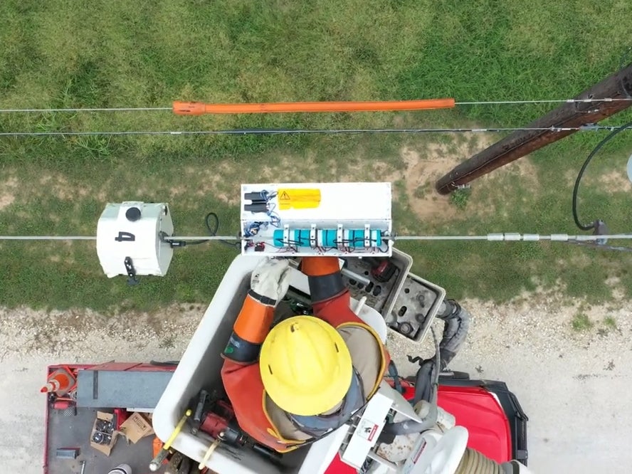 Utility worker installs UT's new grid sensor on an active power line.