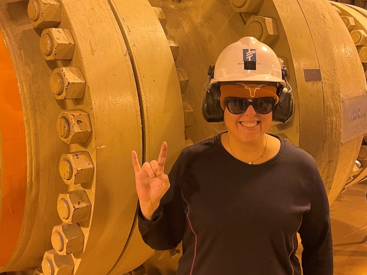 Texas Engineering alumna Jillian Jopling tours a facility in Alaska and poses in front of machinery.