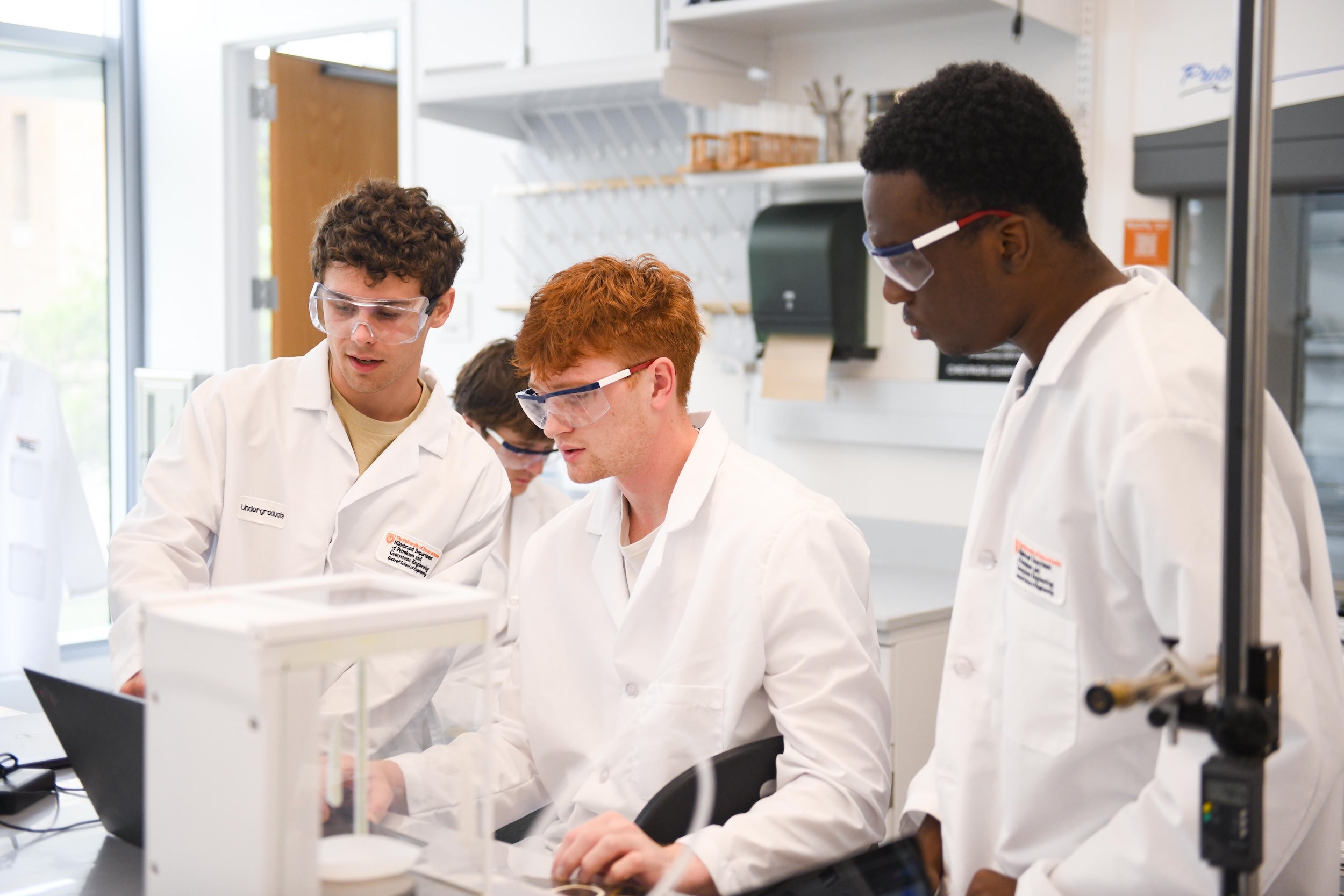 Three students in conducting an experiment in the PGE 427 Properties of Petroleum Fluids lab