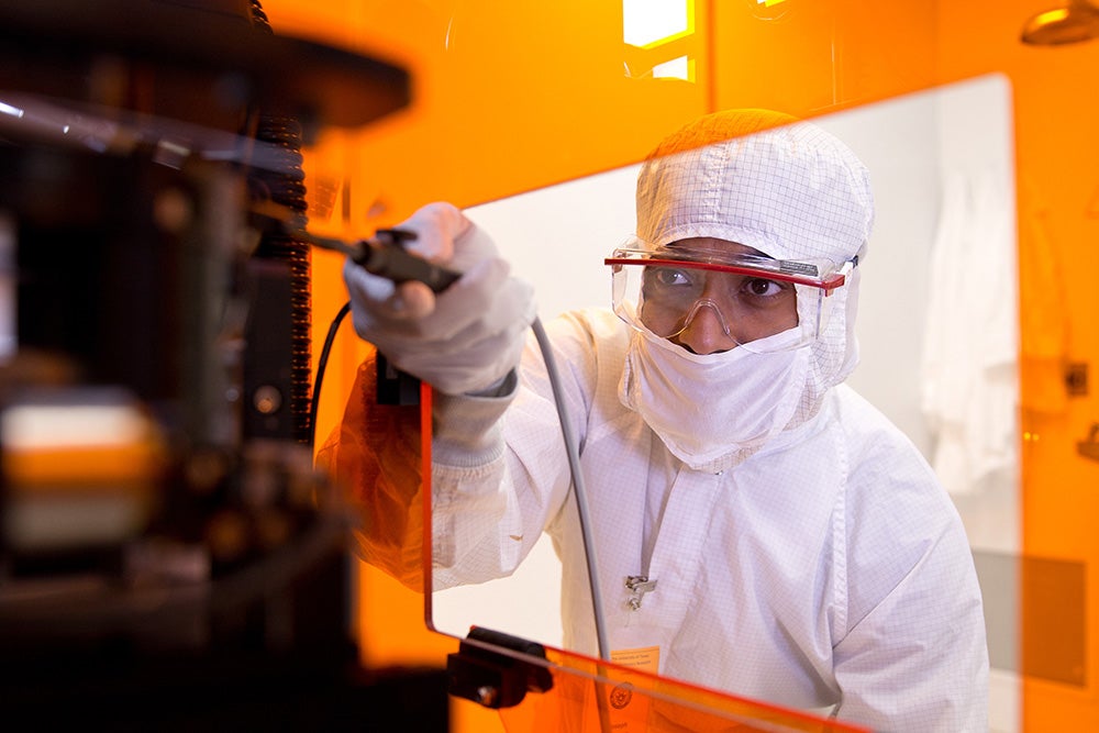 A researcher in a clean lab working with materials.