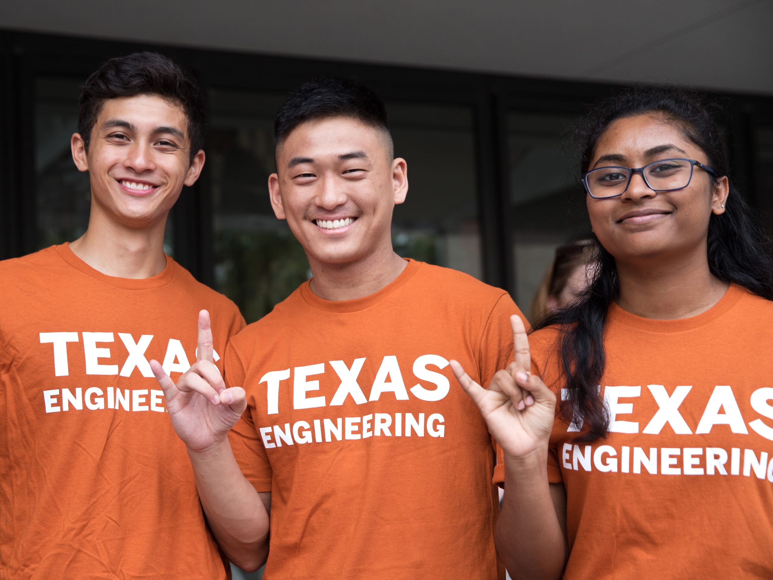 Smiling Texas Engineering students doing hook 'em horns hand signs